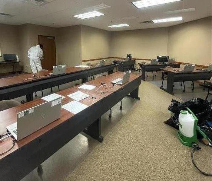 A classroom style set up with workers in PPE cleaning high touched areas